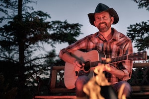 Jason playing guitar near a campfire