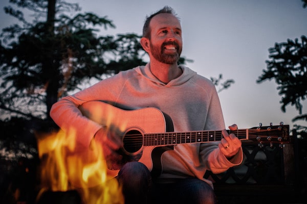 Jason playing a guitar near a campfire