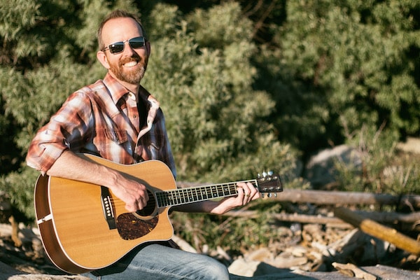 Jason playing a guitar on a beach